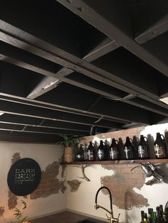 bottles are hanging from the ceiling above a sink in a room with exposed brick walls