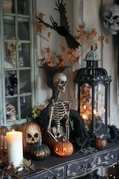 a skeleton sitting on top of a table in front of a window with candles and pumpkins