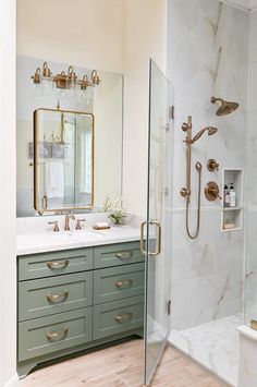 a bathroom with marble counter tops and green cabinetry, along with a walk in shower