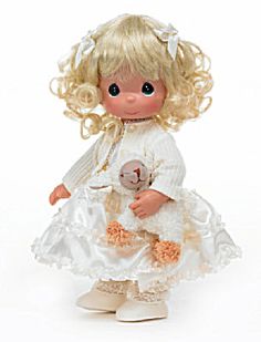 a doll with blonde hair wearing a white dress and holding a teddy bear in her hand