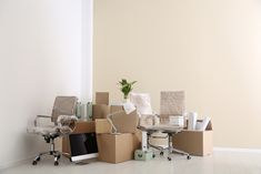 a room filled with boxes and chairs next to a computer on top of a desk