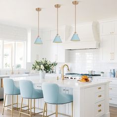 a white kitchen with blue chairs and gold accents on the countertops, along with an island