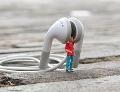 a small toy is standing next to an earbud