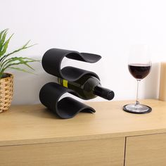 a wine bottle holder sitting on top of a wooden table next to a glass of wine