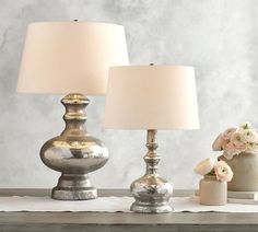 two lamps sitting on top of a wooden table next to a vase filled with flowers