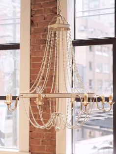 a chandelier hanging from the ceiling in a room with brick walls and windows