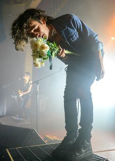 a man standing on top of a stage with flowers in his mouth