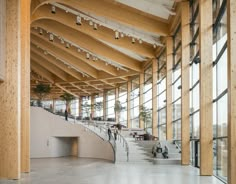 the inside of a large building with many windows and people sitting on benches in it