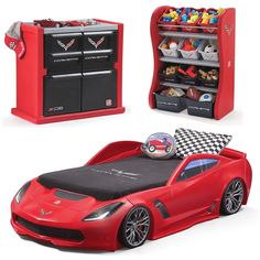 a red toy car bed sitting next to an open bookcase with toys in it