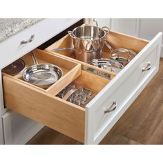 an open drawer in a kitchen with pots and pans on the bottom shelf,