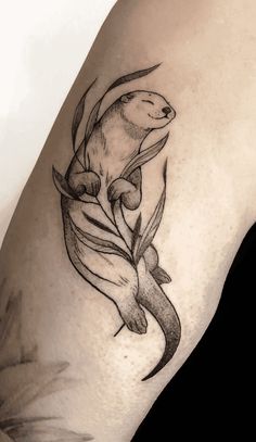 a black and white photo of an animal tattoo on the arm, with leaves around it