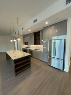 an empty kitchen with stainless steel appliances and wood flooring is seen in this image