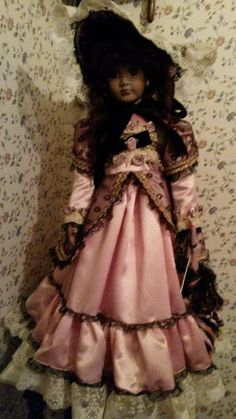 the doll is wearing a pink dress and bonnet