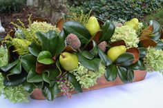 a wooden planter filled with lots of green plants and fruit on top of a table