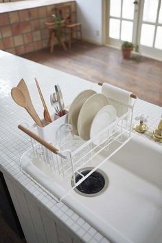 a kitchen sink with dishes and utensils in the dish rack next to it