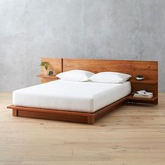 a bed sitting on top of a hard wood floor next to a white pillow and wooden headboard