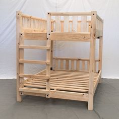 a wooden bunk bed sitting on top of a cement floor next to a white wall