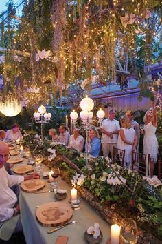 a group of people sitting around a table with food and candles in front of them