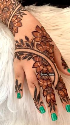 a woman's hand with henna tattoos on it and green nails in the middle