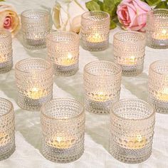 a table topped with lots of glasses filled with candles