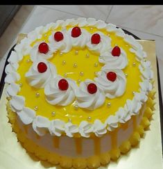 a yellow and white cake with cherries on top