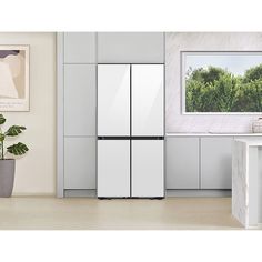 a white refrigerator freezer sitting inside of a kitchen next to a potted plant