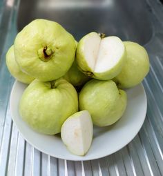 a white plate topped with green apples on top of a metal shelf