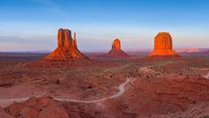 an aerial view of monument buttes in the desert at sunset, with a river running through them