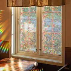 the sun is shining through two windows with flowers on them, and one window has a curtain over it