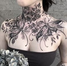 a woman with tattoos on her chest holding a bouquet