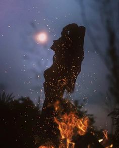 the silhouette of a person standing in front of a fire with lots of sparks coming out of it