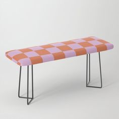 an orange and pink checkered bench sitting on top of a black metal frame legs