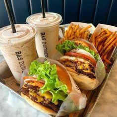 two burgers and fries on a tray with drinks