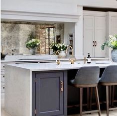 a large kitchen with an island and bar stools in the center, surrounded by white cabinets