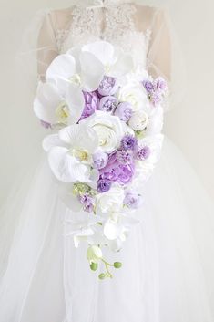 a bride holding a bouquet of white and purple flowers