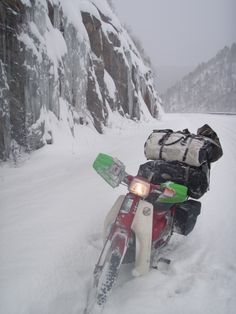 a motorcycle parked in the snow with skis strapped to it's back end