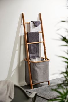 a wooden ladder leaning against the wall with towels in it and a gray bag next to it