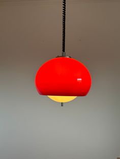 a red light hanging from the ceiling in a room with grey walls and flooring