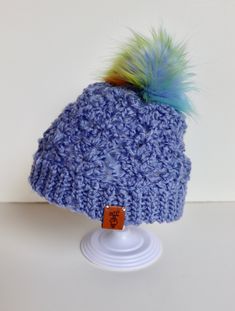 a crocheted hat with a blue and green pom - pom on top