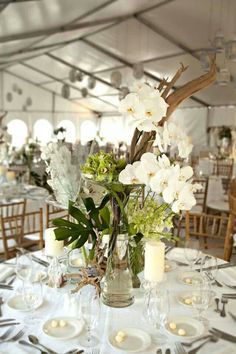 a table set up with flowers and candles for a wedding or special event in a tent