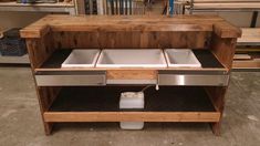 a wooden table with two sinks and an ice chest on it's side in a shop