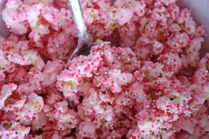 a bowl filled with pink and white sprinkles next to a metal spoon