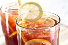 two glasses filled with red liquid and lemon slices