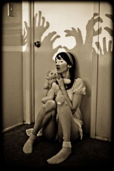 a woman sitting on the floor with her legs crossed and holding two teddy bears in front of her