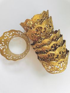 four gold bracelets with dragon designs on them sitting next to each other in front of a white background