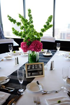 the table is set with plates, silverware and pink flowers in a green vase