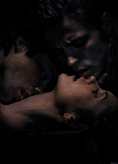 two people are laying down in the dark with their faces close to each other and one person has his eyes closed