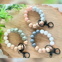 three bracelets with wooden beads and black scissors on a wood board next to a plant