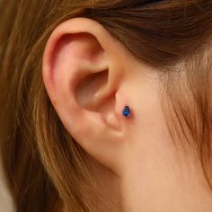 a close up of a person's ear with a blue stone in it