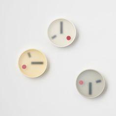 three clocks with different faces are shown on a white surface